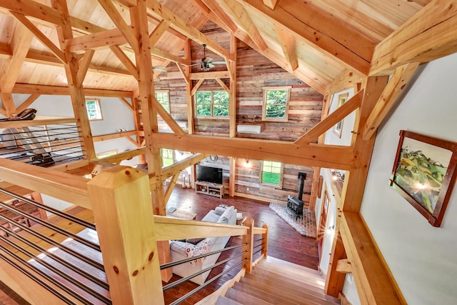 staircase with wood-type flooring, wooden ceiling, beamed ceiling, and a wood stove