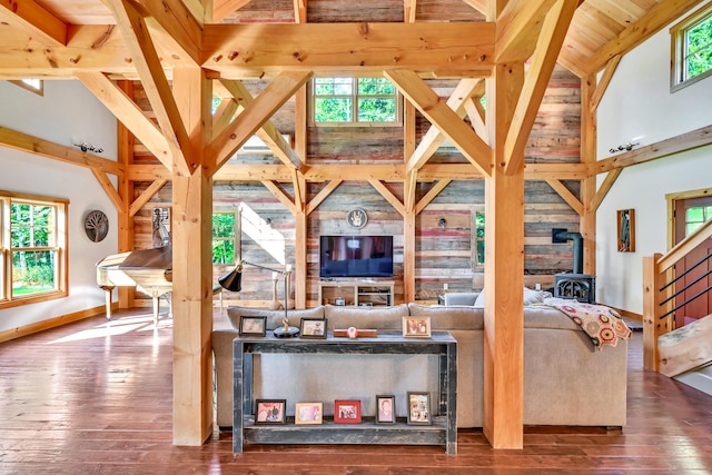 living room with hardwood / wood-style floors, high vaulted ceiling, and a wood stove