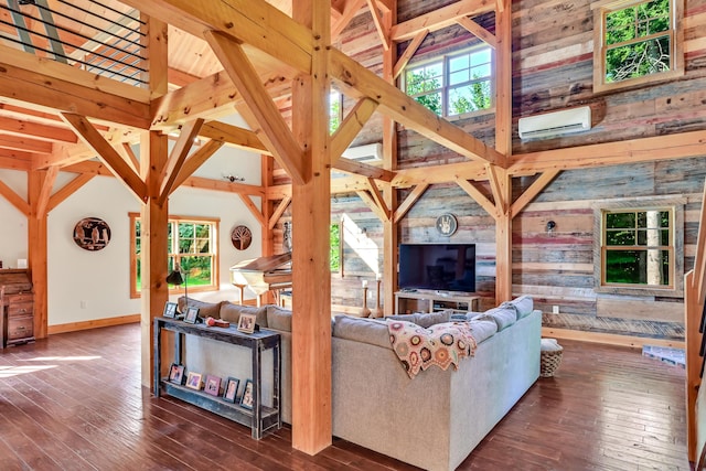 living room featuring a healthy amount of sunlight, dark hardwood / wood-style floors, high vaulted ceiling, and a wall unit AC