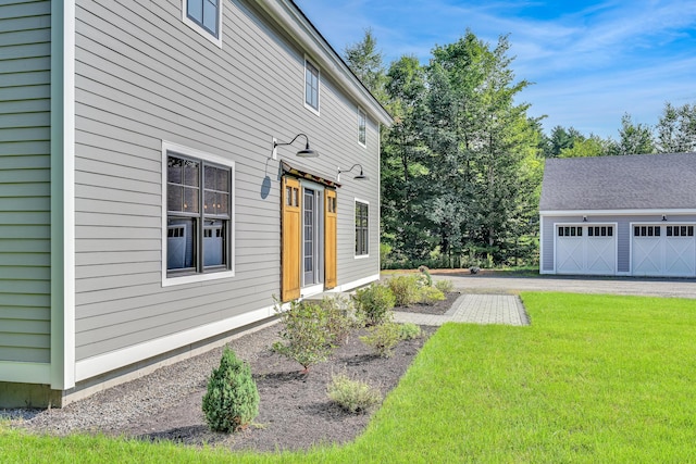 view of side of home with a garage, an outdoor structure, and a lawn