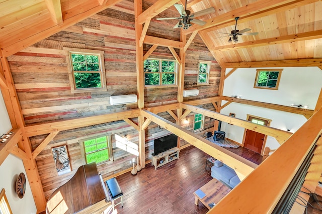 living room with hardwood / wood-style floors, wood walls, lofted ceiling with beams, ceiling fan, and wood ceiling