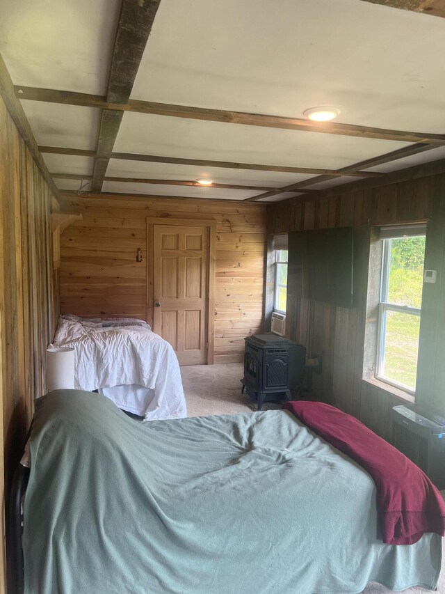 63 Rebel Hill Rd, Merrill, ME 04780 - bedroom with wooden walls, beamed ceiling, a wood stove, and carpet floors