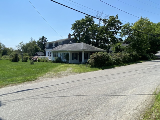 view of front of home featuring a front yard, driveway, and a chimney