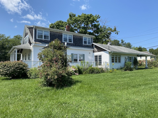 rear view of property featuring a lawn and a chimney