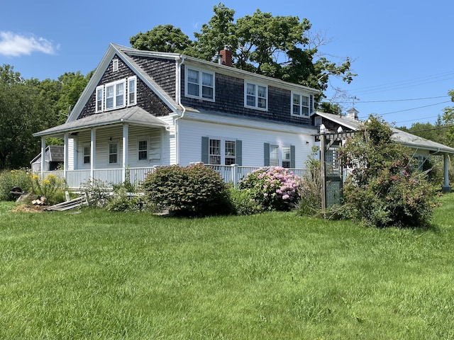view of front of property featuring a front lawn, a chimney, and covered porch