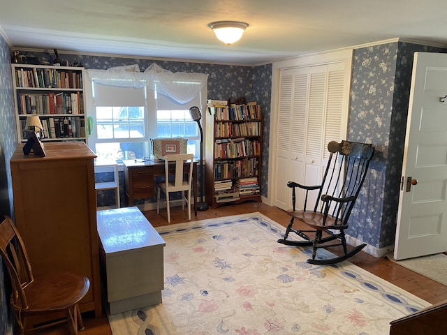 sitting room featuring baseboards, wallpapered walls, wood finished floors, and ornamental molding