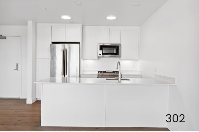 kitchen with white cabinetry, stainless steel appliances, kitchen peninsula, and sink