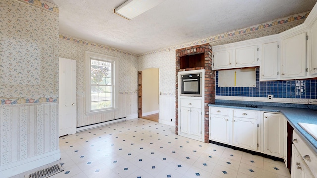 kitchen with white cabinets, a baseboard heating unit, oven, and a textured ceiling