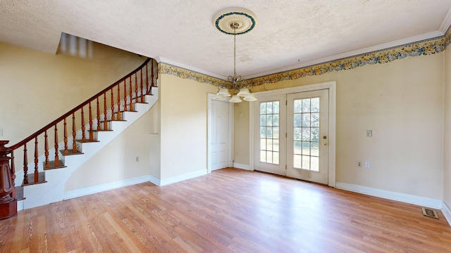 unfurnished dining area featuring an inviting chandelier, hardwood / wood-style floors, ornamental molding, and a textured ceiling