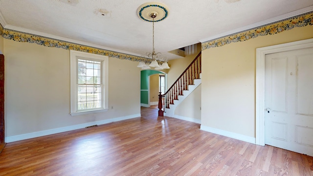 interior space featuring hardwood / wood-style flooring, ornamental molding, and a textured ceiling