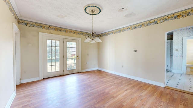 unfurnished dining area with crown molding, a notable chandelier, a textured ceiling, and light wood-type flooring