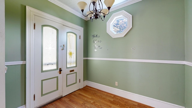 entrance foyer with light hardwood / wood-style flooring, ornamental molding, and a chandelier