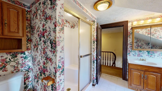 bathroom with toilet, a shower with shower door, a textured ceiling, vanity, and tile patterned flooring