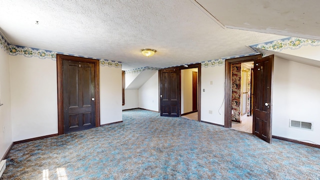 interior space with vaulted ceiling, carpet floors, and a textured ceiling