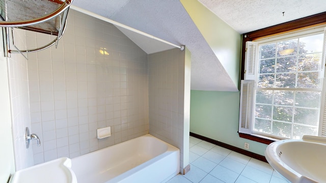 bathroom with tile patterned floors, tiled shower / bath combo, vaulted ceiling, and a textured ceiling