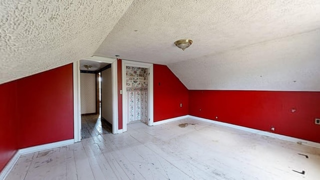 bonus room with lofted ceiling, a textured ceiling, and light hardwood / wood-style flooring