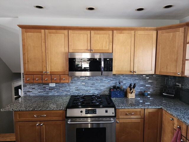 kitchen featuring appliances with stainless steel finishes, backsplash, and dark stone counters