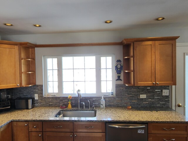 kitchen featuring sink, stainless steel dishwasher, decorative backsplash, and light stone counters