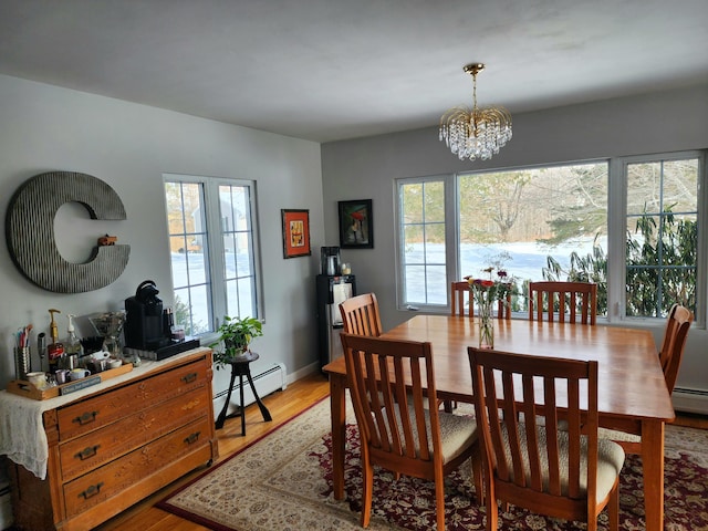dining area with a baseboard radiator, light wood-type flooring, baseboards, and a chandelier