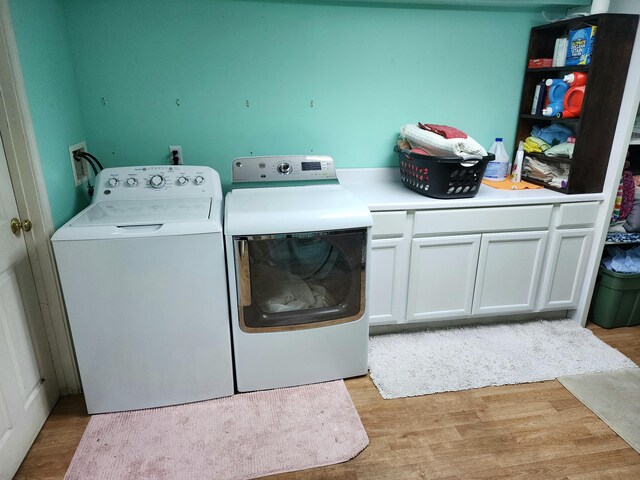 washroom featuring cabinets, separate washer and dryer, and light wood-type flooring