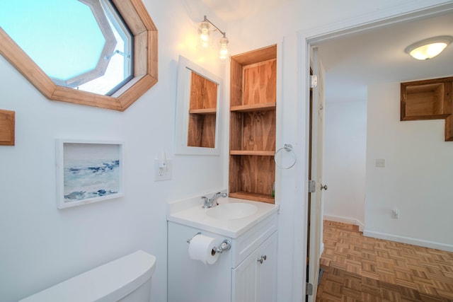 bathroom featuring baseboards, vanity, and toilet