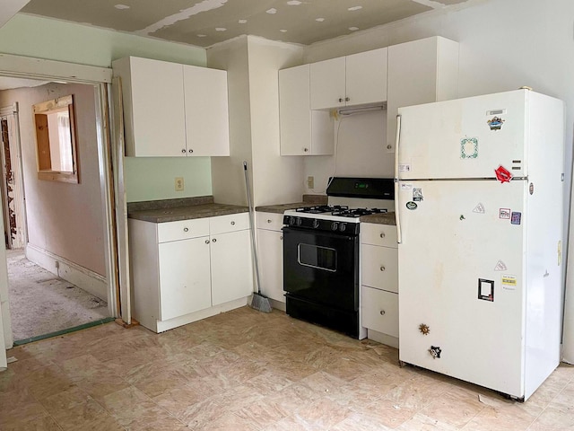 kitchen with gas range oven, dark countertops, freestanding refrigerator, and white cabinets