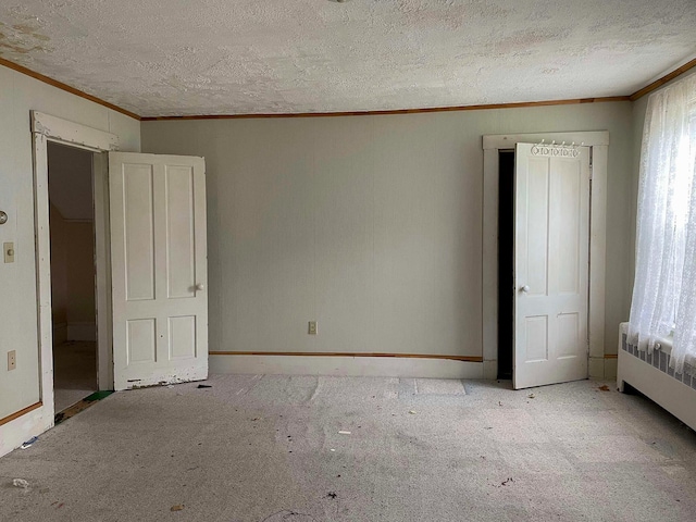 unfurnished bedroom featuring crown molding, a textured ceiling, carpet, and radiator