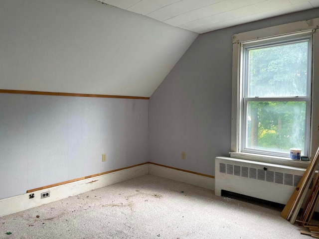 additional living space with radiator, baseboards, carpet flooring, and lofted ceiling