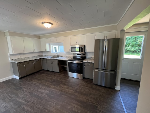 kitchen with light stone counters, white cabinetry, appliances with stainless steel finishes, and sink