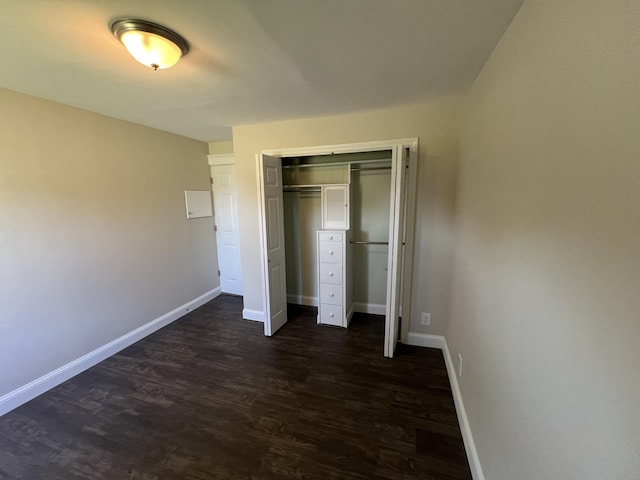 unfurnished bedroom with dark wood-type flooring and a closet