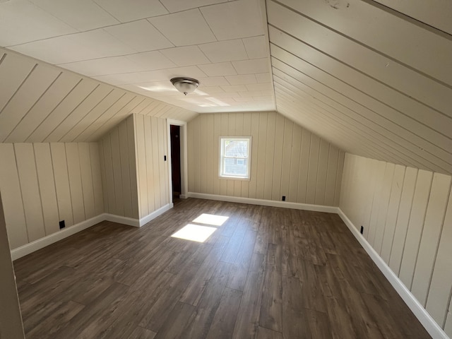 additional living space with wooden walls, lofted ceiling, and dark hardwood / wood-style floors