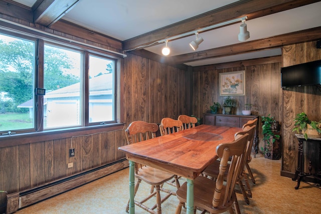 dining room with wooden walls, baseboard heating, track lighting, and light carpet