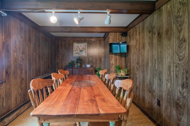 carpeted dining space with beamed ceiling, a baseboard heating unit, rail lighting, and wooden walls