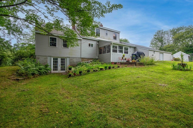 back of house featuring a lawn and french doors