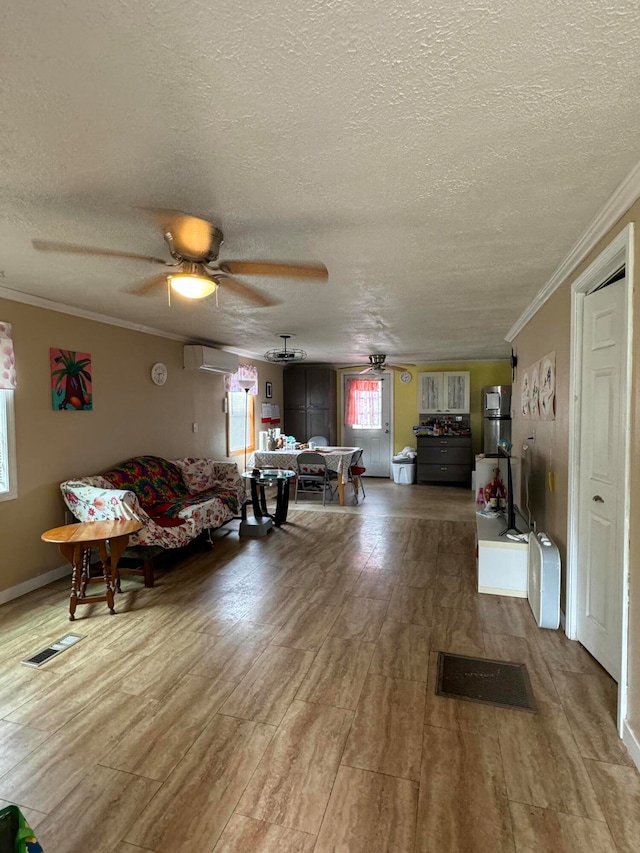 living room with a textured ceiling, crown molding, a wall unit AC, and ceiling fan