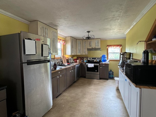 kitchen with light tile patterned flooring, a textured ceiling, stainless steel appliances, and ornamental molding