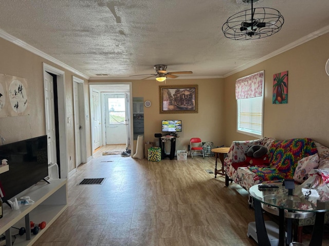 tiled living room with a textured ceiling, ceiling fan, and crown molding