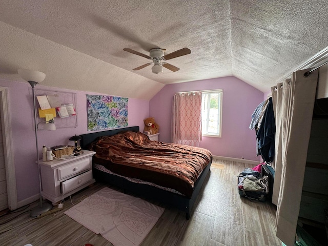 bedroom featuring a textured ceiling, wood-type flooring, ceiling fan, and lofted ceiling