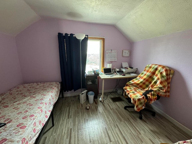 bedroom featuring a textured ceiling, light hardwood / wood-style flooring, and vaulted ceiling