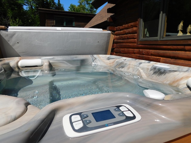 exterior space featuring rustic walls and a hot tub