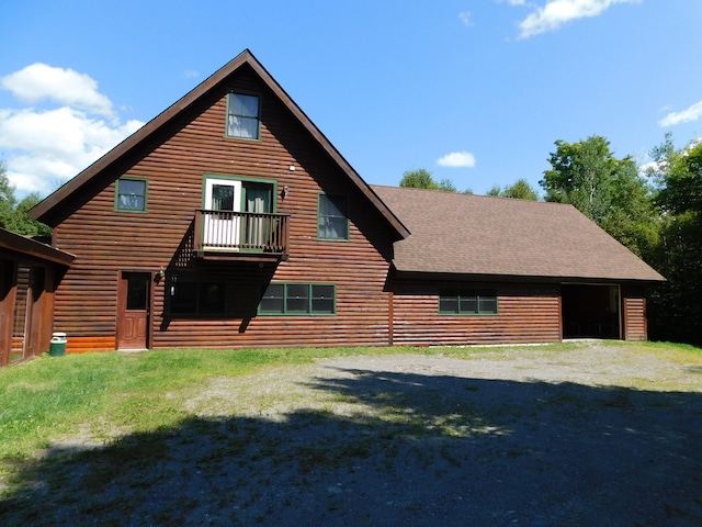 back of house with a lawn and a balcony