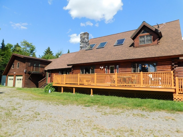 61 Sawyer Pond Highlands, Greenville, ME 04441 - back of property with a garage, log siding, a chimney, a deck, and roof with shingles