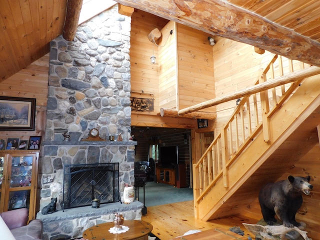 carpeted living room with high vaulted ceiling, a fireplace, wooden walls, and wood ceiling