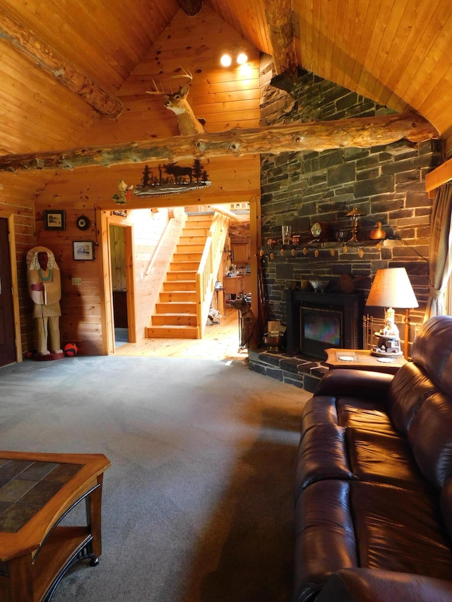 living room with a stone fireplace, carpet, wooden walls, beamed ceiling, and wood ceiling