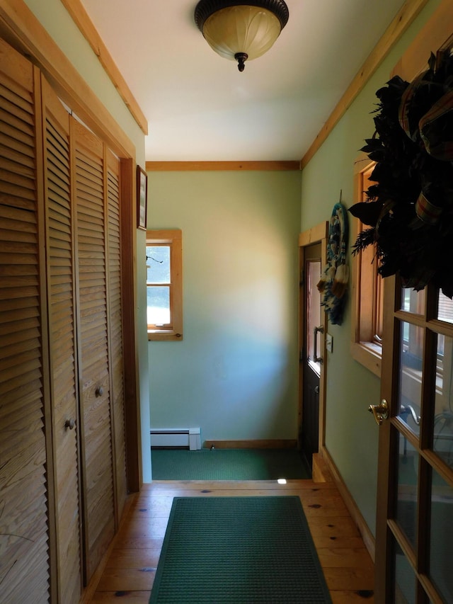 entryway with baseboard heating, ornamental molding, and hardwood / wood-style flooring