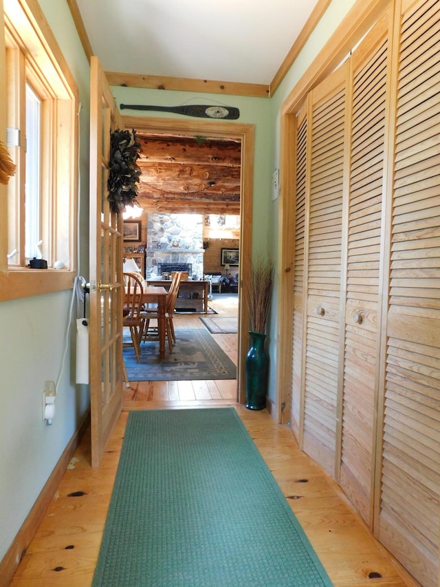 corridor featuring light wood-type flooring and ornamental molding