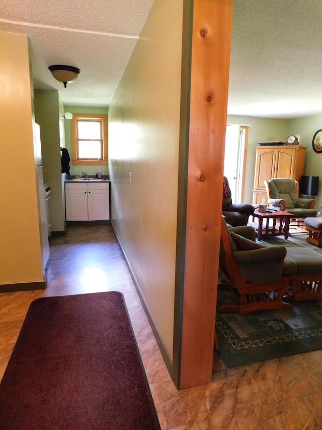 corridor featuring sink and a textured ceiling