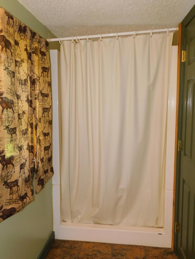 bathroom featuring tile patterned flooring, a textured ceiling, and curtained shower