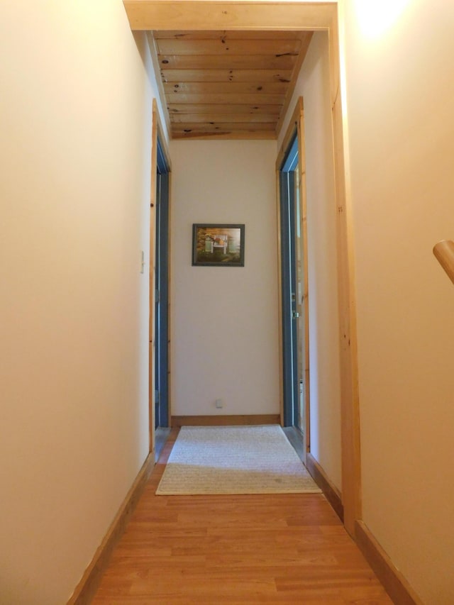 corridor featuring light hardwood / wood-style flooring and wooden ceiling