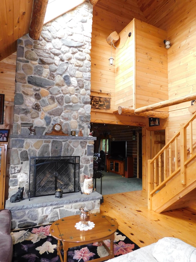 carpeted living room with beam ceiling, a fireplace, wooden walls, and wood ceiling